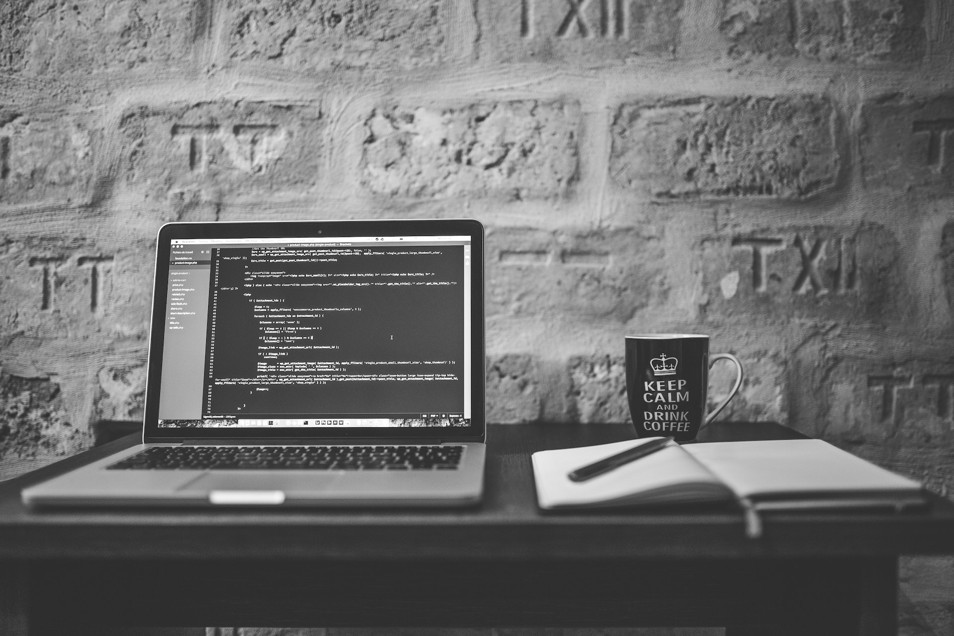 Grayscale photo of computer laptop near white notebook and ceramic mug on table banner-8104